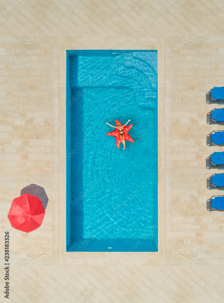 Aerial view of woman on star shapes inflatable mattress in swimming pool. Aerial view of woman on star shapes inflatable mattress in swimming pool.