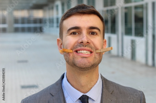Businessman with clothespins creating a fake smile 