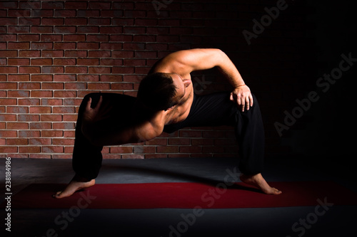 Man doing the pose of yoga Parivritta Stambhasana photo