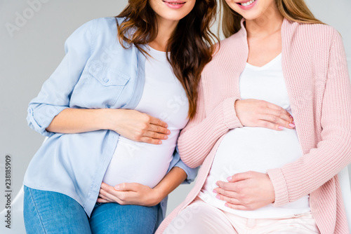 cropped view of pregnant smiling women sitting on antenatal class isolated on grey
