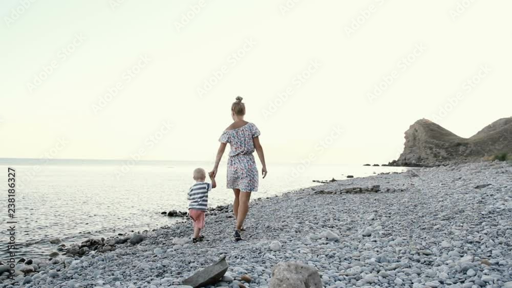 a woman with a little boy walking along the shore a woman with a little boy walking along the shore