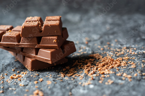 Selective focus Broken chocolate pieces and cocoa powder on stone background