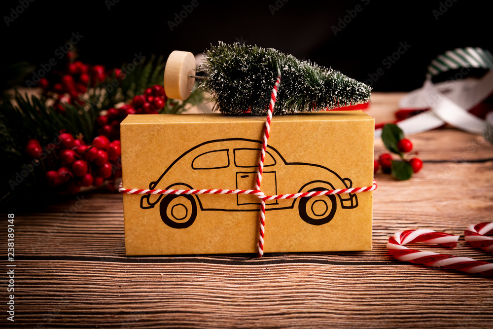Prezent świąteczny. Świąteczny prezent z symbolem samochodu na drewnianym stole, kompozycja z miejscem na tekst. - obrazy, fototapety, plakaty 