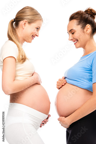 two pregnant women holding hands on bellies and smiling each other isolated on white © LIGHTFIELD STUDIOS