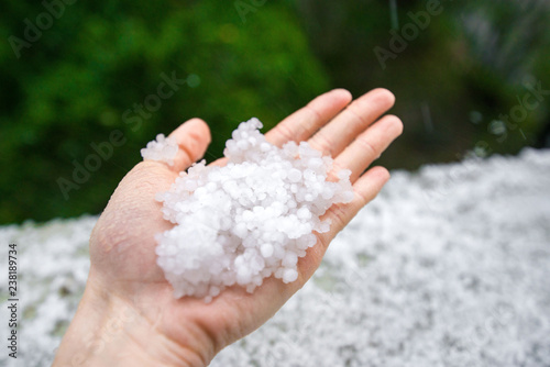 Holding freezing granulated hail ice crystals, grains in hands after strong hailstorm in autumn, fall. First snow in early winter. Cold weather. 