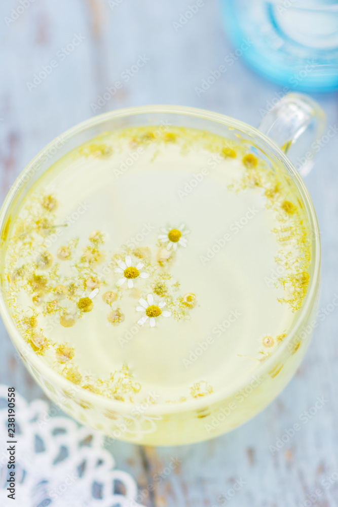 Fresh chamomile blossom tea in a glass cup on a wooden table, healthcare and healthy eating concept Fresh chamomile blossom tea in a glass cup on a wooden table, healthcare and healthy eating concept