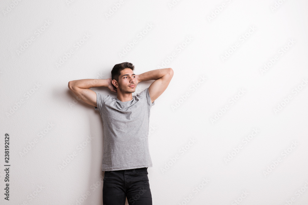 Cheerful young hispanic man standing in a studio, hands behind head. Copy space. Cheerful young hispanic man standing in a studio, hands behind head. Copy space.