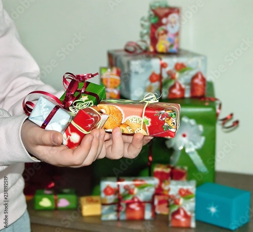 Cute little hands of a child holding mini colorful packed boxes for Christmas presents and gifts. Holidays and family concept.