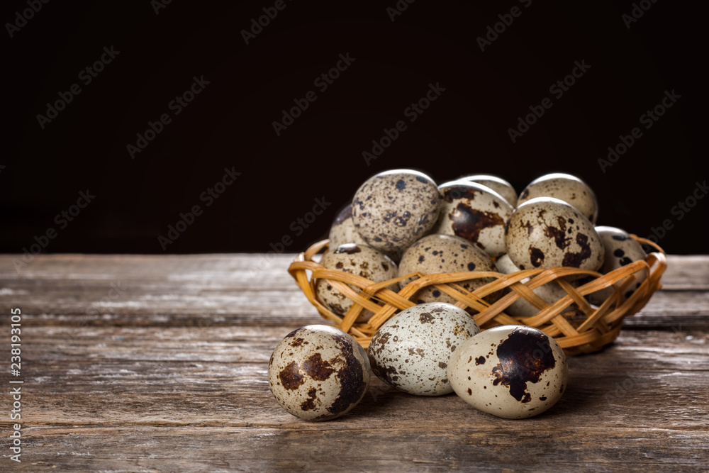 Quail eggs in wicker basket on wooden background Quail eggs in wicker basket on wooden background