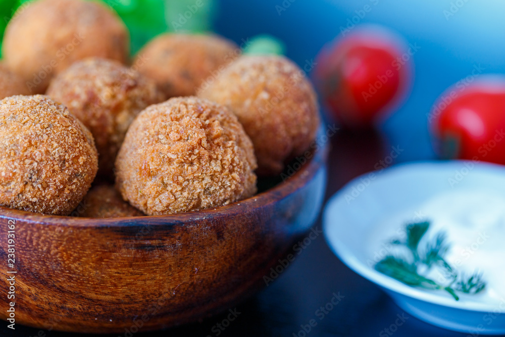 Falafel lies in a wooden plate. On the table lie tomatoes, cucumbers, lettuce, dill, lemon, sour cream. Falafel lies in a wooden plate. On the table lie tomatoes, cucumbers, lettuce, dill, lemon, sour cream.