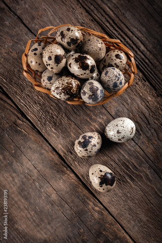 Quail eggs in wicker basket on wooden background