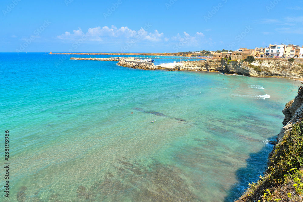 beautiful landscape with small coastal town Terrasini and beach calarossa with Faraglioni di Praiola with turquoise blue water and cloudy blue sky with mountains in background, Sicily Italy Palermo