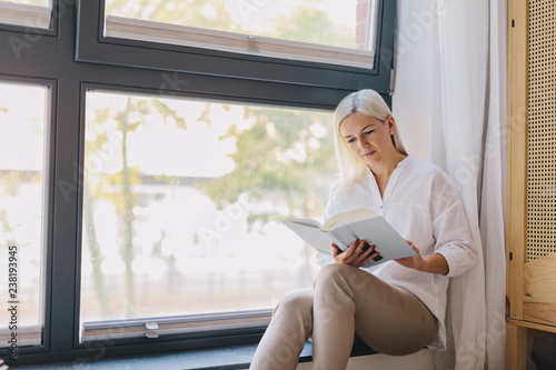 Woman reading book at home by the window. Free Download Woman reading book at home by the window. - GFXLoad
