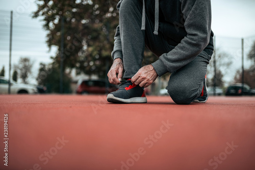 Low angle image of male runner tying shoelaces on tartan track.