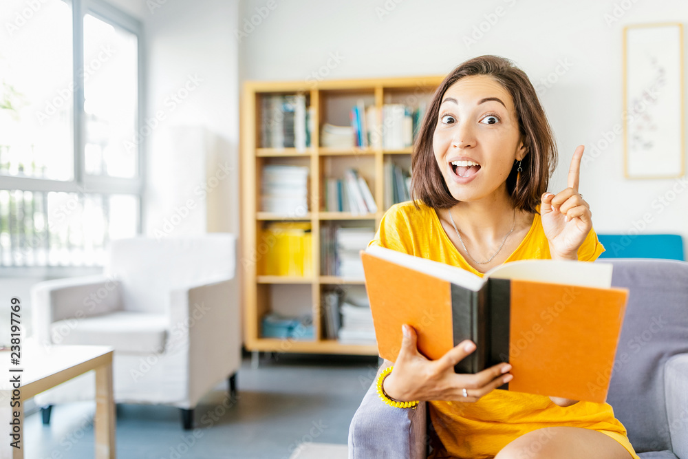 Education concept. Happy student woman thinking and having interesting idea while reading book in library Education concept. Happy student woman thinking and having interesting idea while reading book in library
