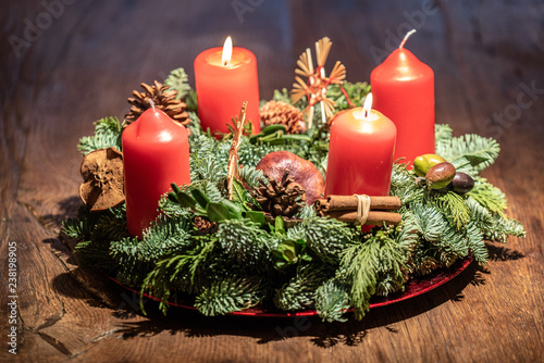 advent wreath and two burning red candles on a wooden table Studio