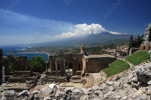 dymiący wulkan etna na sycylii z niebieskim morzem i ruinami starożytnego włoskiego miasta w tle w słoneczny dzień
