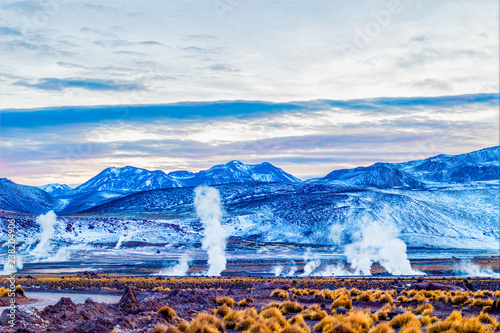 In the morning steam and smoke of the Geysers Del Tatio, mountains, blue vegetation and yellow vegetation landscape, July 12, 2018, Atacama Desert, Chile. photo
