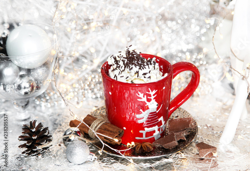 Christmas, xmas red cup of whipped cream on shiny plate, and metallic background, with chocolate, sweets, cinnamon, winter cone, lights and balls