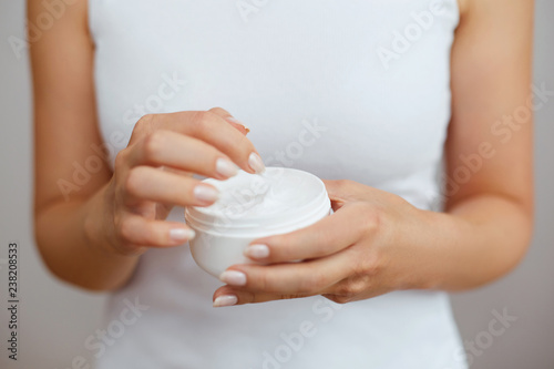 Closeup shot of woman hands holding cream and applying moisturizing hand cream. Beautiful female hands with cream. Hand Skin Care. A woman uses body lotion on your arms. Beauty And Body Care Concept