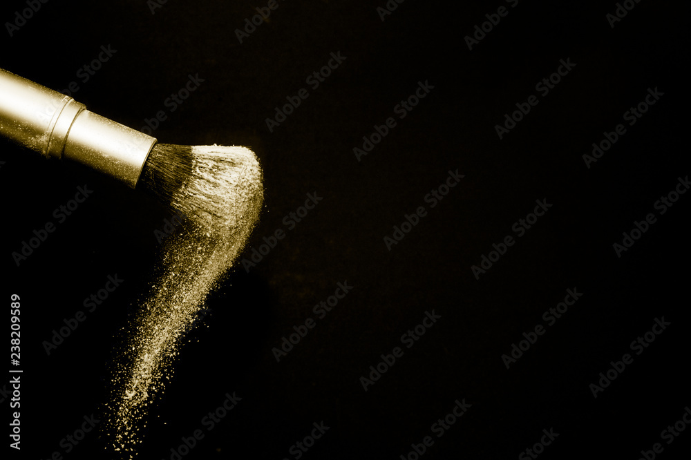 gold powder splash and silver brush for makeup artist or beauty blogger in black background, look like a luxury mood. gold powder splash and silver brush for makeup artist or beauty blogger in black background, look like a luxury mood.