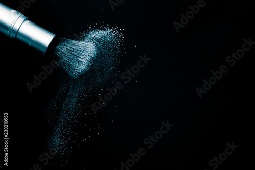 Deep ocean powder color splash and silver brush for makeup artist or beauty blogger in black background, look like a look like a cold and calm mood. © pariwatpannium