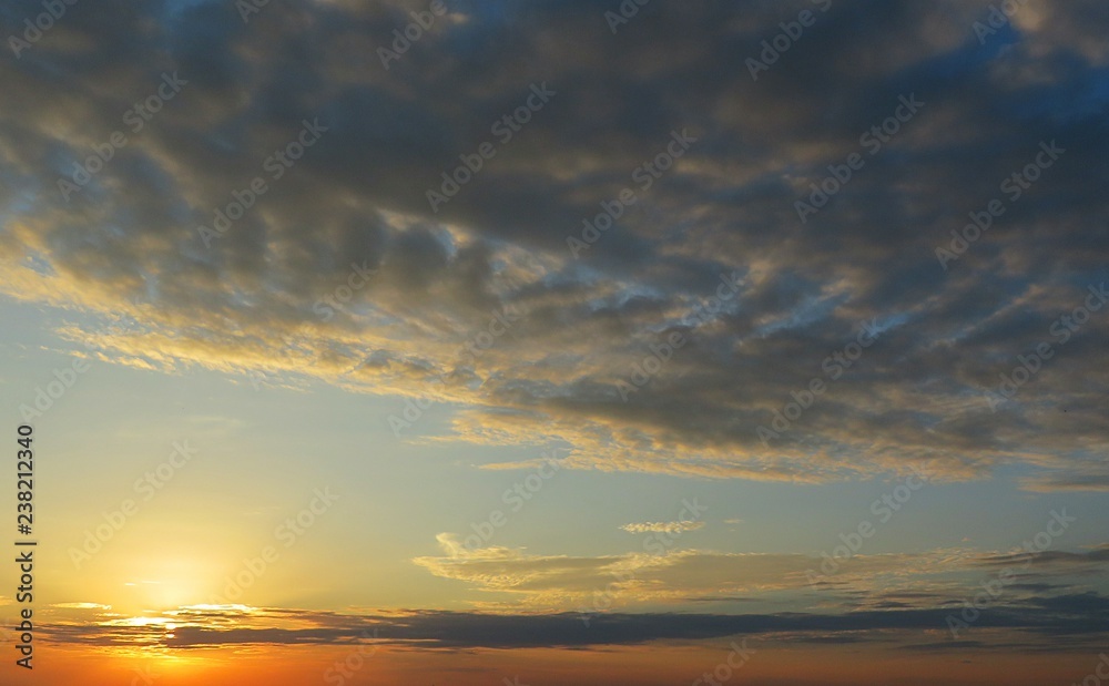 Beautiful yellow sunset background with dark clouds 