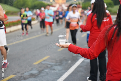 Fototapeta Naklejka Na Ścianę i Meble -  Close up of volunteers hands offering water during a Marathon. Use of selective focus. Lots of Copyspace.