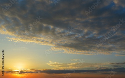 Beautiful yellow sunset background with dark clouds 
