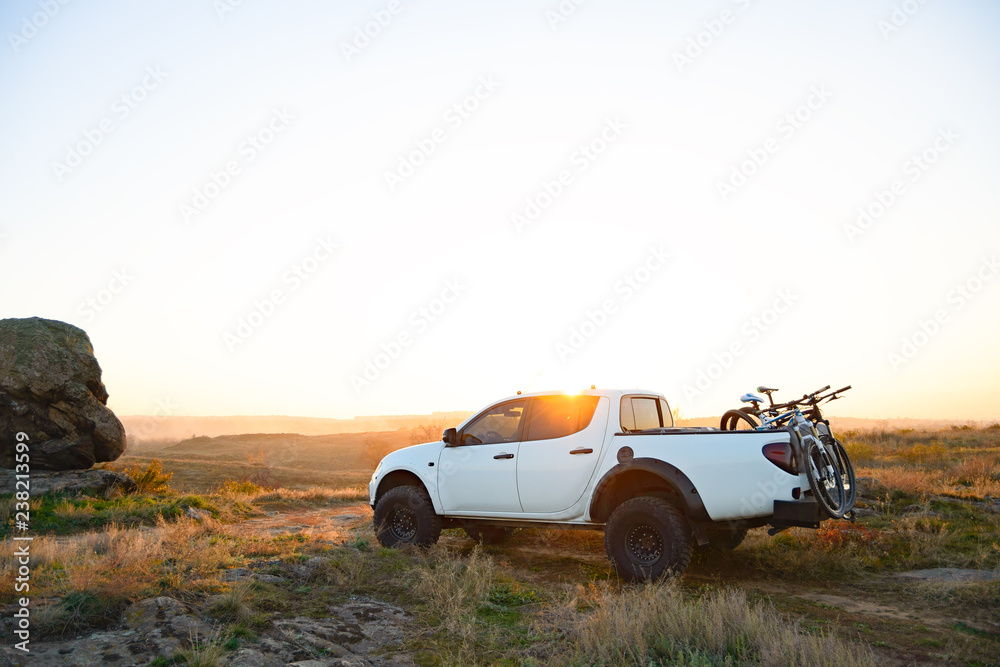 Pickup Offroad Truck with Bikes in the Body in the Mountains at Sunset. Adventure and Car Travel Concept. - obrazy, fototapety, plakaty 