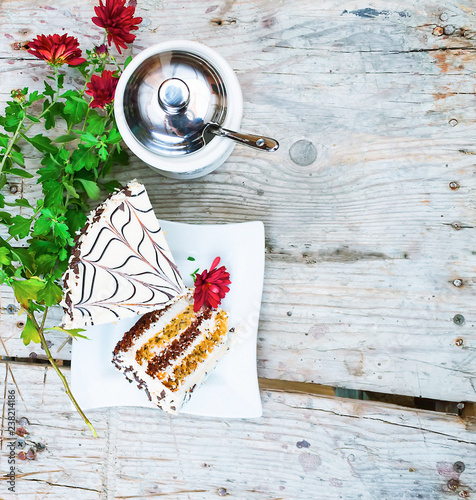 A piece of delicious cake with flowers on a wooden background