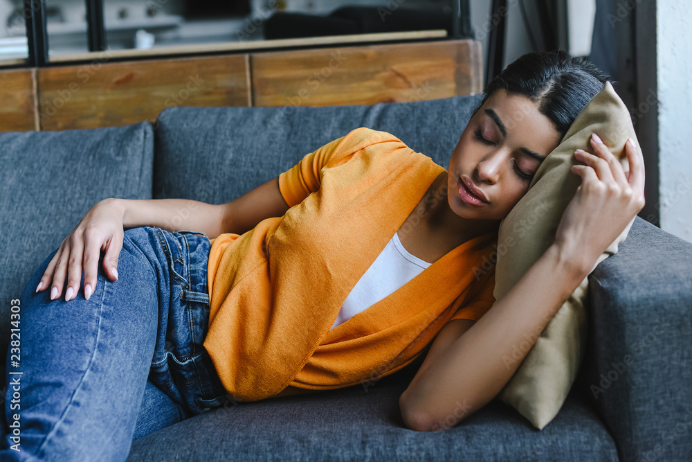 beautiful mixed race girl in orange shirt and jeans sleeping on sofa at  home Stock Photo | Adobe Stock