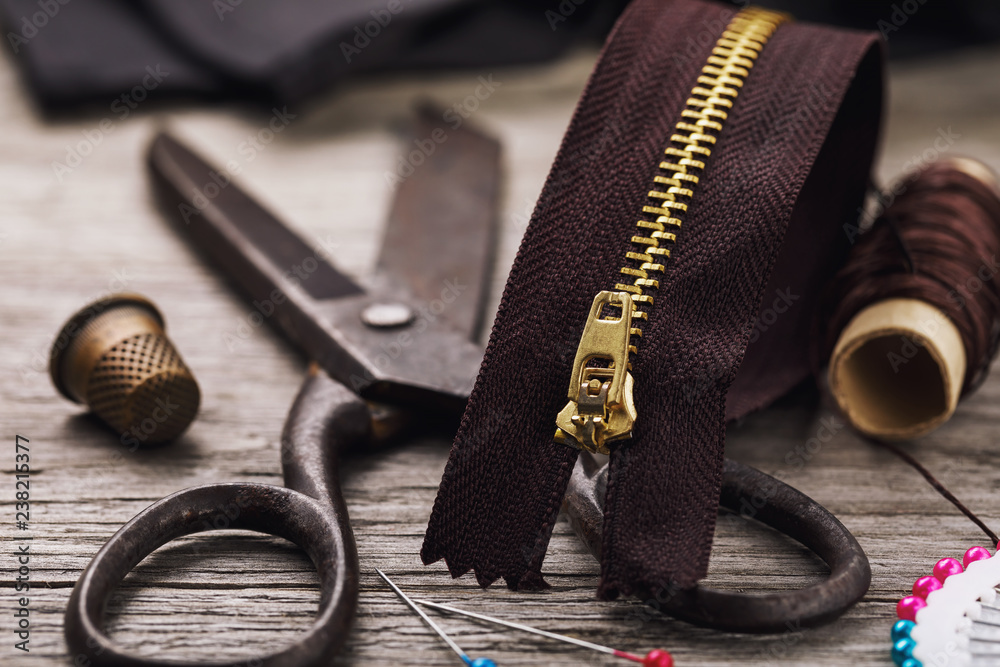 Zipper for clothes close-up and repair tools on a wooden table Zipper for clothes close-up and repair tools on a wooden table