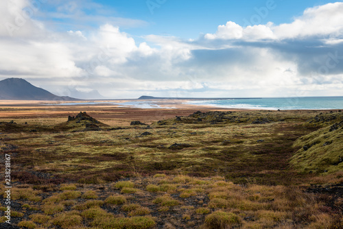 Coastal Scenery in Iceland with a Lava Field in Foreground under Blue Sky with Clouds in Autumn