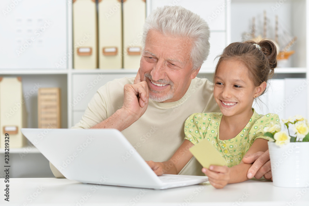 Portrait of grandfather and granddaughter using laptop together Portrait of grandfather and granddaughter using laptop together