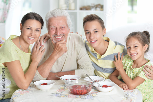 Portrait of happy family eating fresh strawberries