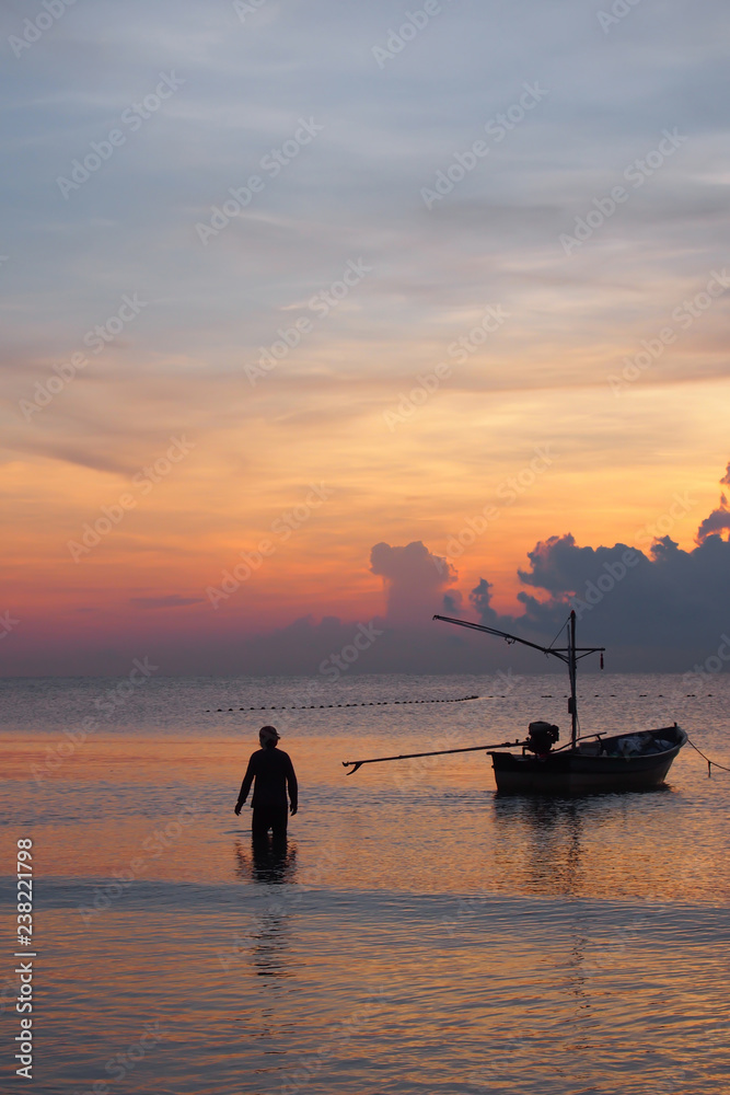 Sunrise, the colors of the morning sky, with the fishermen preparing the boat to go out to fish.