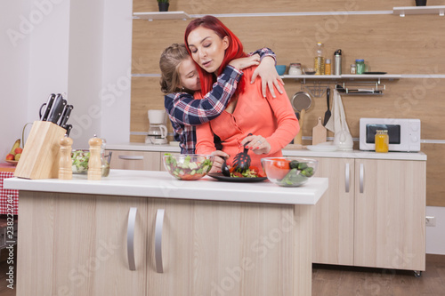 Mother and daughter having a sweet moment while cooking. Strong conection. photo