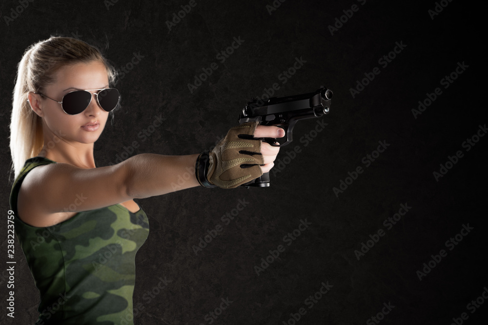 Sexy girl wearing military style posing with guns and sunglases isolated in studio Sexy girl wearing military style posing with guns and sunglases isolated in studio