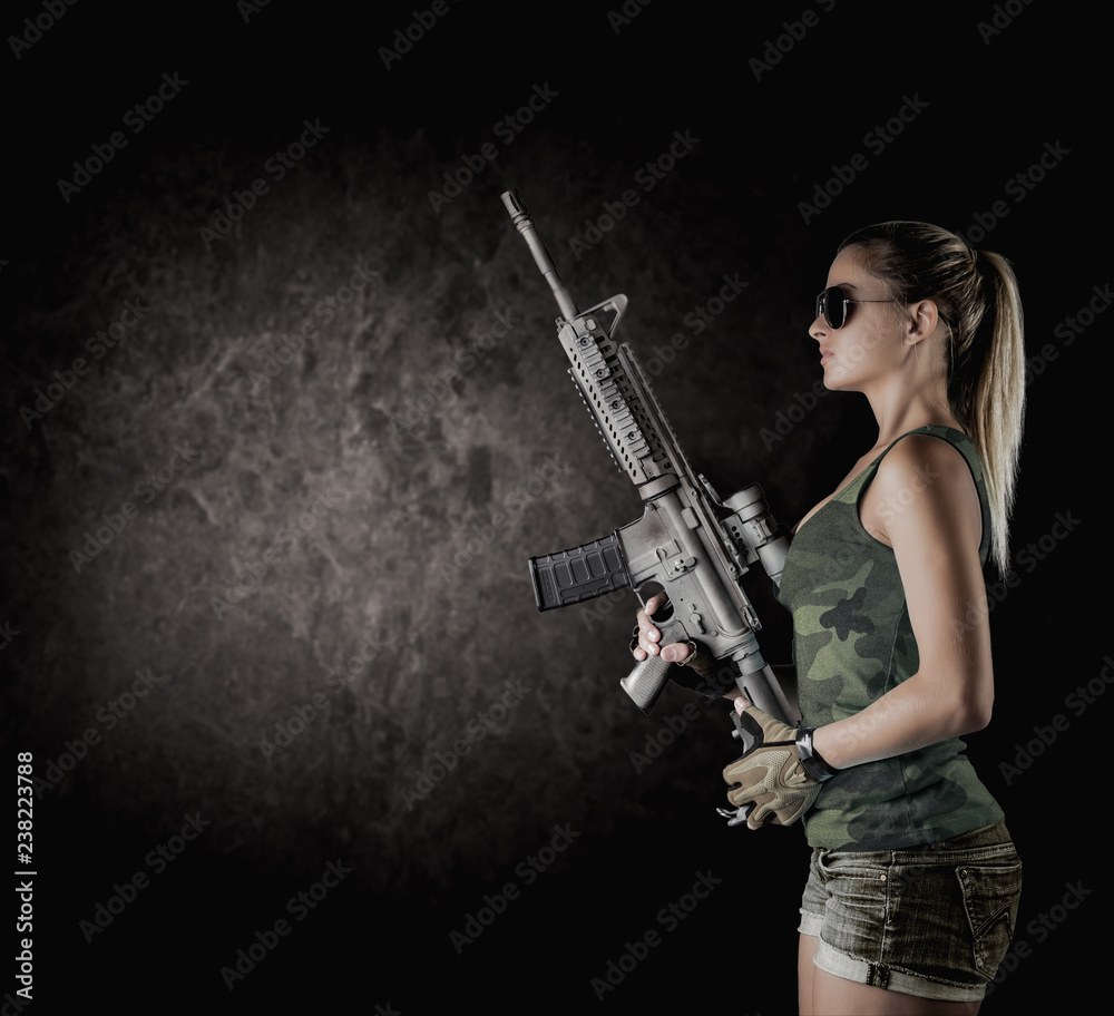 Sexy girl wearing military style posing with guns and sunglases isolated in studio