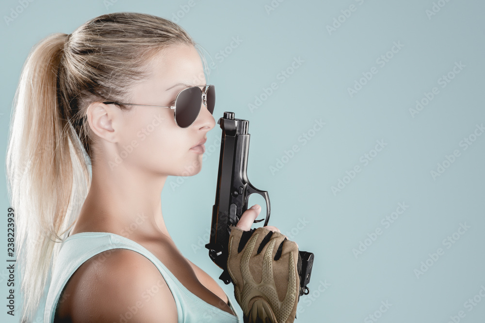 Sexy girl wearing military style posing with guns and sunglases isolated in studio Sexy girl wearing military style posing with guns and sunglases isolated in studio