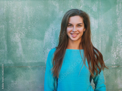 Portrait of a beautiful young caucasian girl. A woman in a blue sweater against the backdrop of a blue wall, a place for text