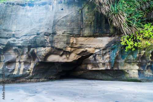 a small cave in the rock above the sandy beach photo