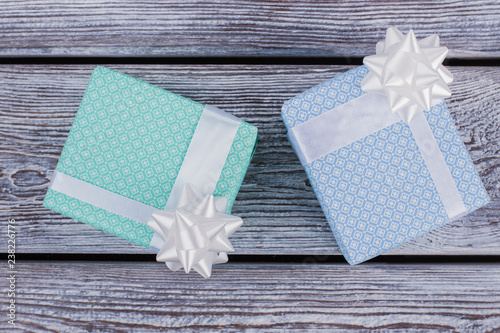 Two gift boxes on wooden background. Top view on gift boxes packed in light festive paper. Christmas gifts background.