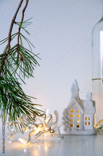 Scandinavian Christmas decor. pine branches, garland and a ceramic house lamp