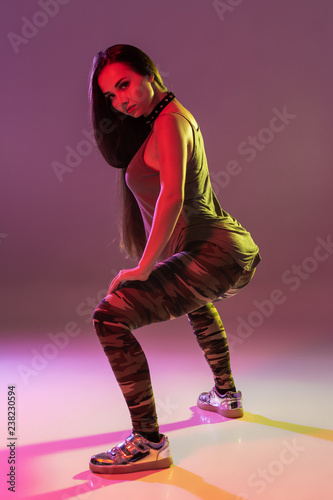Attractive young brunette woman in the studio dancing Booty dance on a dark background