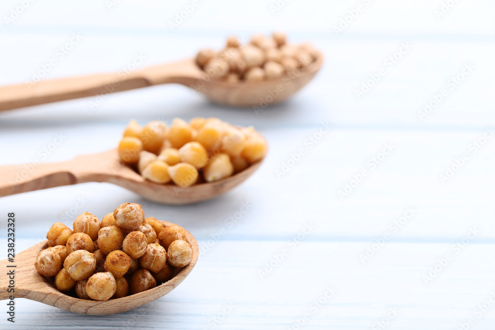 Roasted chickpeas in spoons on wooden table