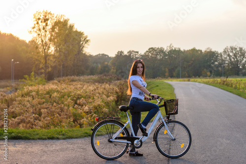 Active woman riding bicycle at autumn day. Sunset/