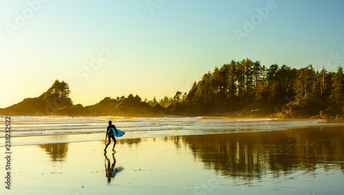 Ein Surfer geht an einem Strand auf Vancouver Island entlang