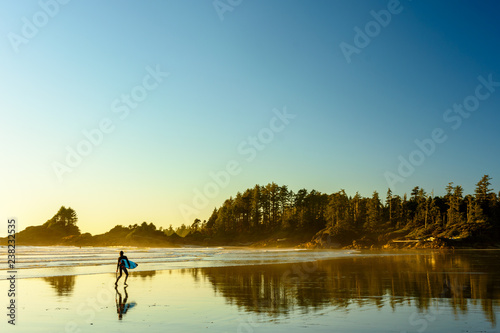 Ein Surfer geht an einem Strand auf Vancouver Island entlang photo